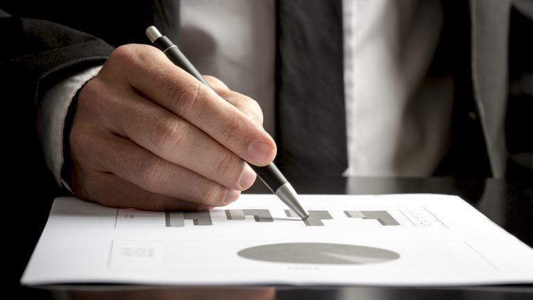 Closeup of financial consultant reviewing statistical graphs and charts of annual income and profit of a business company.